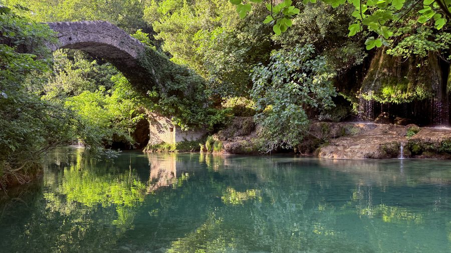 The medieval bridge over the Siagne, its arch reflected in green water