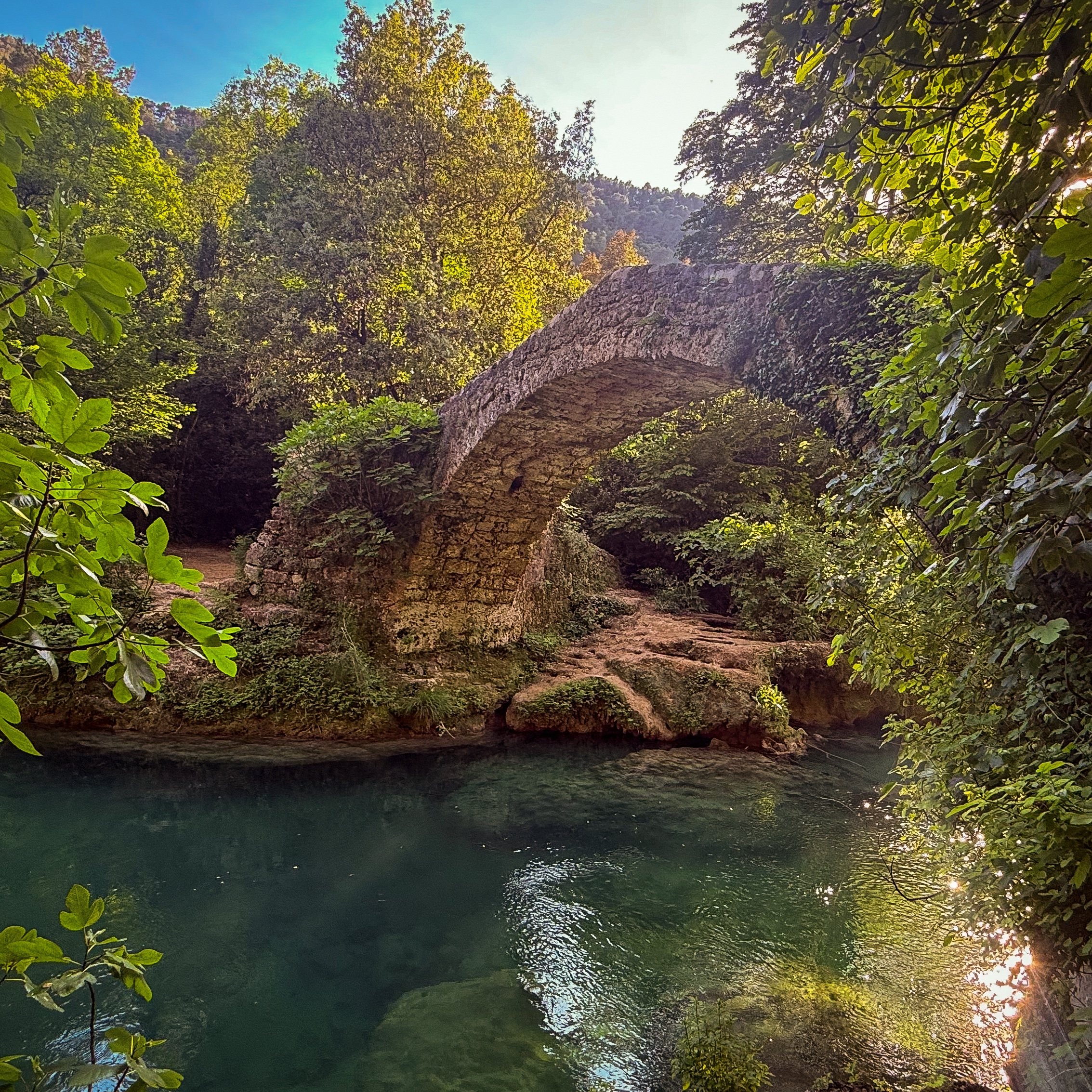 The medieval Pont des Tuves, also called Pont des Gabres, arching over the green water of the Siagne river between Saint-Cézaire and Montauroux